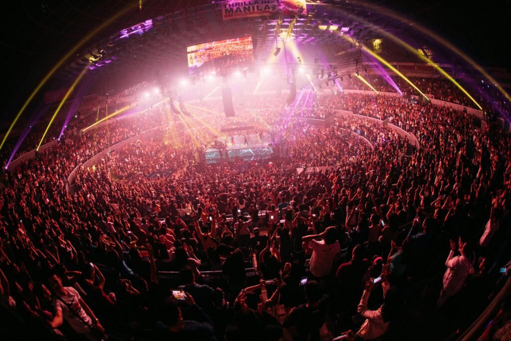 Vibrant crowd enjoying a live concert in a bustling Manila arena at night.