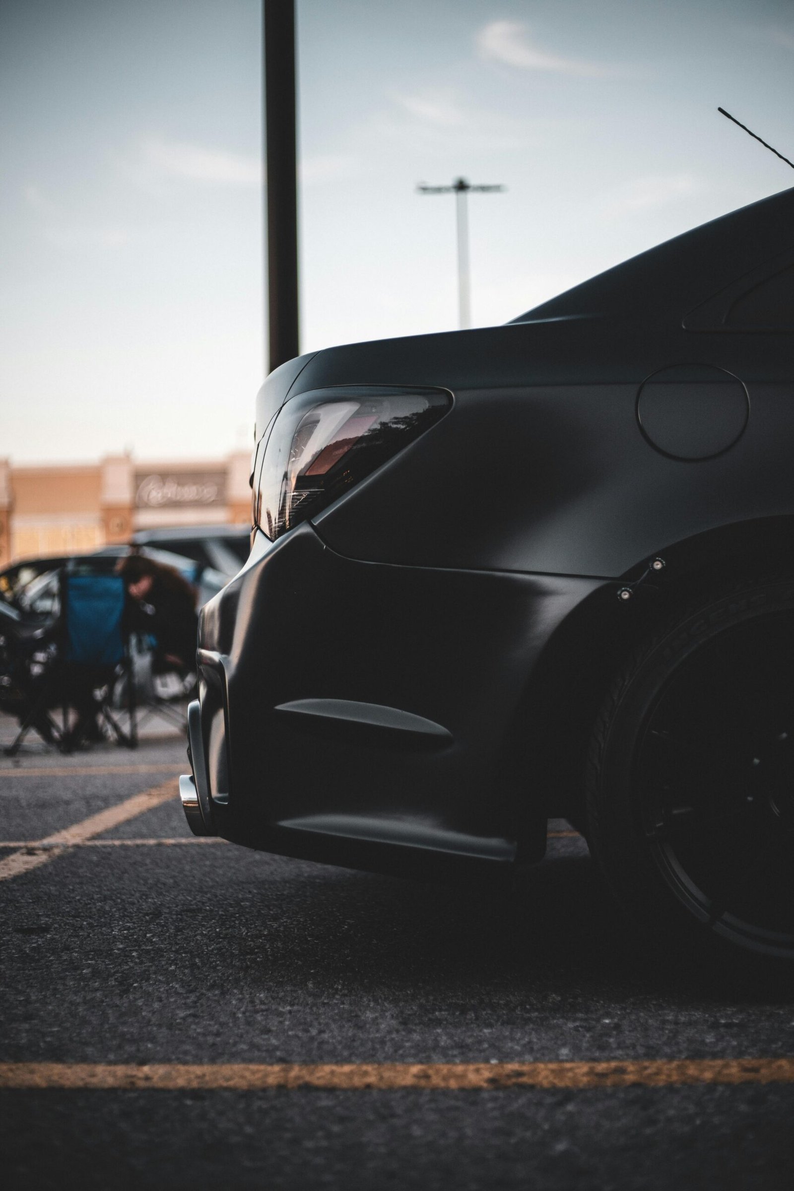 Sleek black car with custom features parked in a city lot, capturing urban elegance and automotive design.
